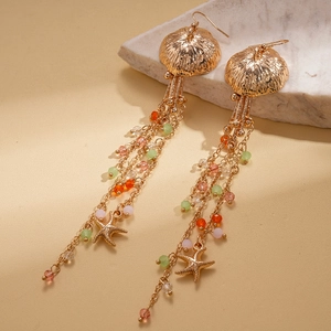 Detail of beaded jellyfish and starfish tassel earrings on marble background