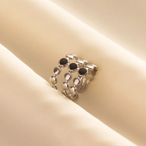 Detail of silver beaded triple-layer ring with black enamel dots on satin fabric