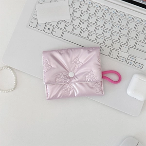 Close-up of pink quilted satin bow pouch used as a portable coin and earphone storage bag