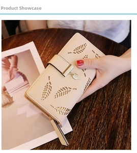 Detail of leaf pattern cutout and gold leaf pendant on long beige faux leather wallet