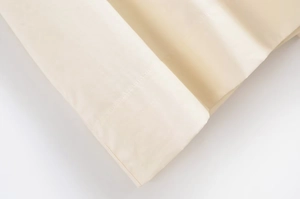 Macro detail of beige silk-like fabric showing precise stitching and smooth texture