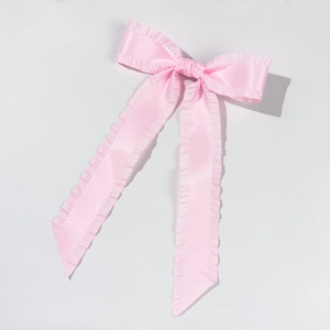 Detailed close-up of pink silk bow hair clip with elegant ruffled ribbon edges
