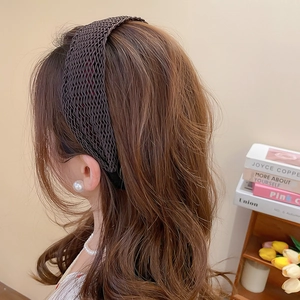 Close-up of a coffee brown woven wide headband on wavy hair with elegant pearl details