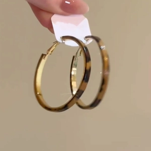 Detailed close-up of tortoise shell pattern hoop earrings with gold inner metal lining