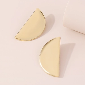 Detailed top view of gold minimalist half-moon geometric stud earrings on pink background