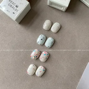 Set of four speckled press-on nails in various colors with short square-oval shapes