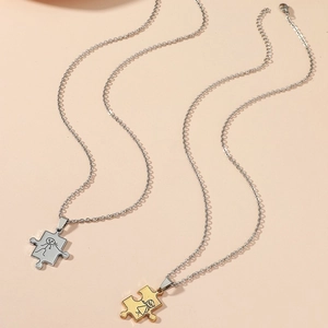 Dettaglio di collane cuore puzzle argento e oro per coppie con figure incise
