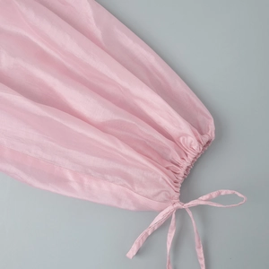 Detail of pink semi-transparent lantern sleeve with pleated cuffs and drawstring tie