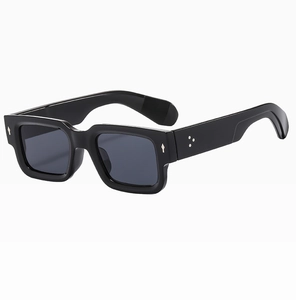 Détail de lunettes de soleil carrées noires avec points métalliques et monture brillante