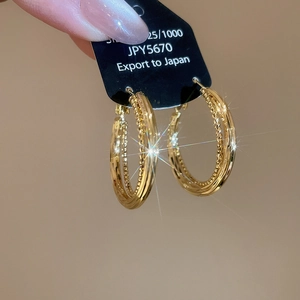 Detailed close-up of golden S925 sterling silver hoop earrings with spiral twist texture