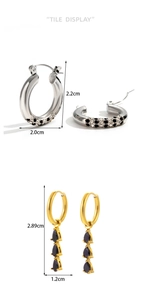 Detailed view of silver diamond-encrusted hoop and golden earrings with black teardrop gems