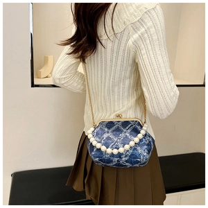 Detail of blue denim frame bag with quilted pattern, pearl handle and gold chain strap