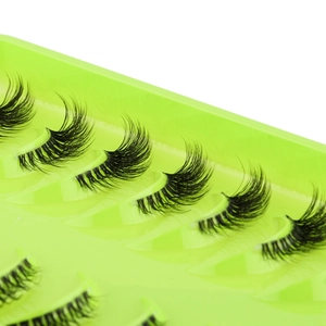 Macro detail of natural half-strip false eyelashes on a vibrant neon green tray