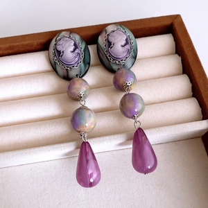 Macro detail of vintage resin earrings with purple cameo and marbled beads in a display box