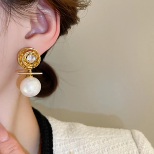 Détail des élégantes boucles d'oreilles fleur plaquées or et perles portées