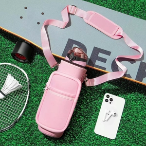 Pink neoprene water bottle sleeve with adjustable shoulder strap and pocket on green grass