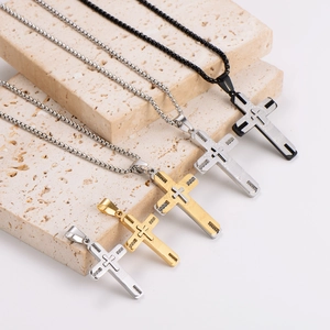 Cross pendant necklaces in black, gold, and silver on stone steps with box chains