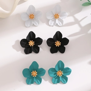 Detailed view of matte flower earrings in white, black, and teal with golden centers