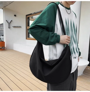 Close-up of black oxford cloth crossbody bag on a model in an outdoor urban setting
