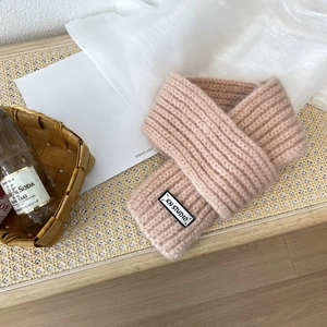 Pink ribbed knit scarf detail featuring a white woven label on a lifestyle background