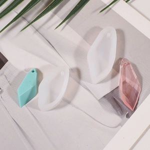 Macro shot of geometric resin stone molds with faceted pendant samples on a magazine