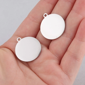 Polished silver stainless steel round pendant blank held by hand for scale and detail