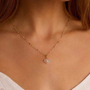 Pink heart pendant necklace with gold chain and colorful beads on a model