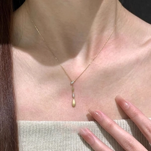 Close-up of a gold water-drop pendant necklace with zircon on a model's neckline