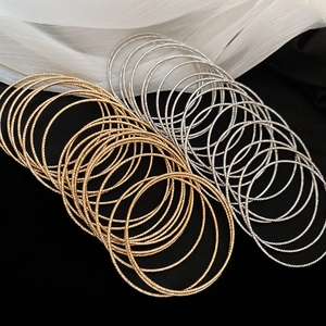 Macro detail of textured gold and silver stackable bangles on a pleated fabric background