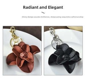 Detail view of premium leather camellia flower keychains in brown and black with metal hardware