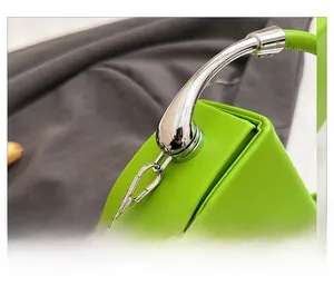 Detailed close-up of shiny green leather saddle bag with polished silver hardware detail
