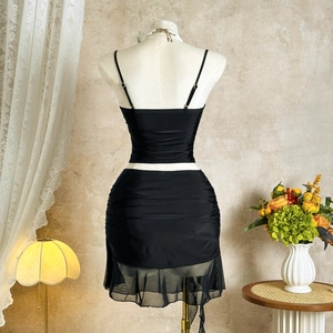 Rear view of black camisole set featuring ruched mini skirt with sheer mesh hem detail