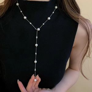 Close-up of elegant Y-shaped long pearl necklace on a black turtleneck sweater