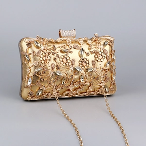 Detailed close-up of golden luxury evening clutch with hollow floral patterns and rhinestones