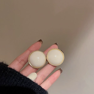 Gros plan sur des boucles d'oreilles vintage en résine beige avec bordure dorée