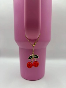 Red cherry charm keychain with green leaves on a pink tumbler handle decoration