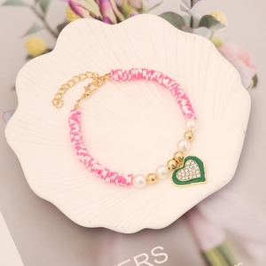 Detailed shot of multi-color heishi bead bracelet with a rhinestone heart charm in a tray