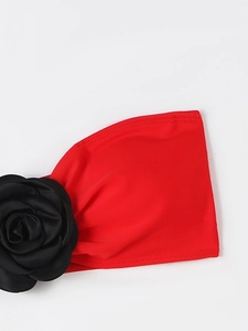 Detail of red bikini top featuring a large black 3D satin rose flower and elastic fabric