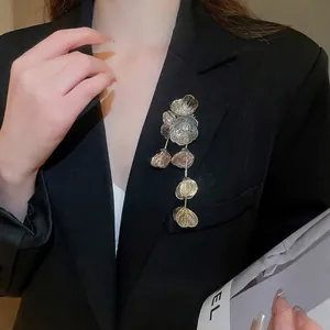 Elegant gold hollow flower brooch with crystal tassels on a black suit blazer
