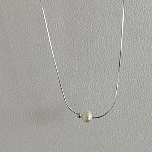 Detail of a 925 sterling silver chain with a white pearl and silver bead pendant