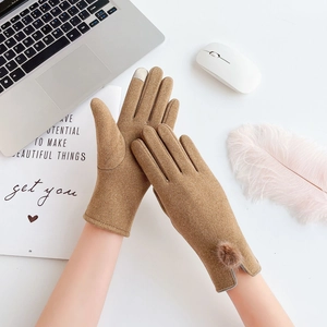 Close-up of camel knit gloves featuring plush faux fur pompom and touchscreen fingertips