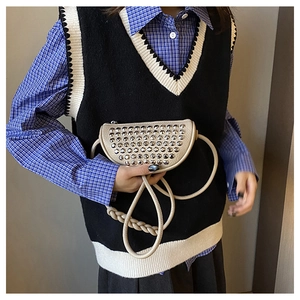 Detailed view of silver rivets on off-white half-moon bag with braided strap details