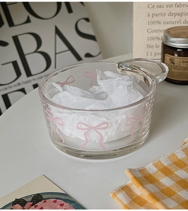 Detailed close-up of a glass bowl featuring a pink bow pattern and an elegant handle