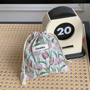 Close-up of floral drawstring pouch with tulip pattern on woven mat with vintage calendar