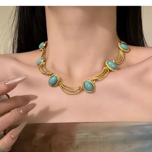 Close-up of vintage gold necklace with turquoise stones worn on a model's neckline