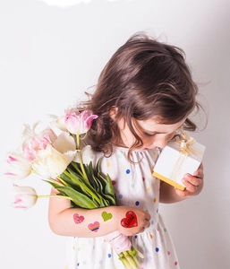 Fillette tenant des tulipes avec tatouages de cœur pour la fête des mères sur le bras