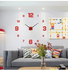 Macro detail of DIY wall clock with red acrylic numbers and black hands on a grey sofa background