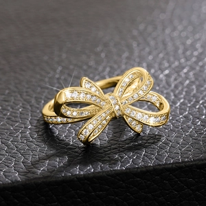 Vue macro d'une bague nœud dorée sertie de zircons sur un fond texturé sombre