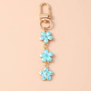 Detail of light blue enamel cherry blossom charms on a golden keychain and ring
