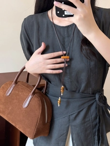 Détail des perles en bois et pendentif orange sur collier long avec robe en lin grise